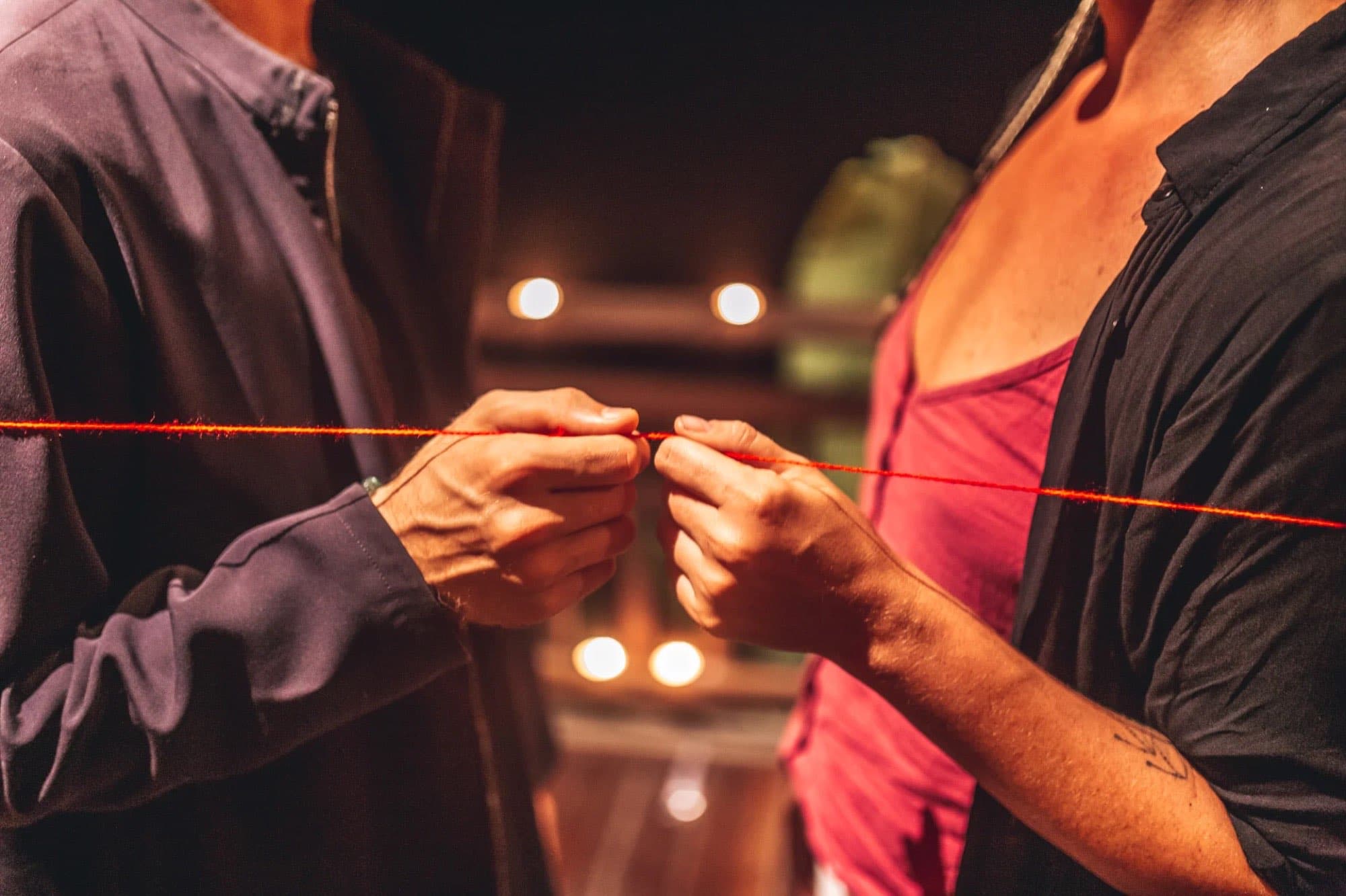 Two people connected by a red thread in a practice space